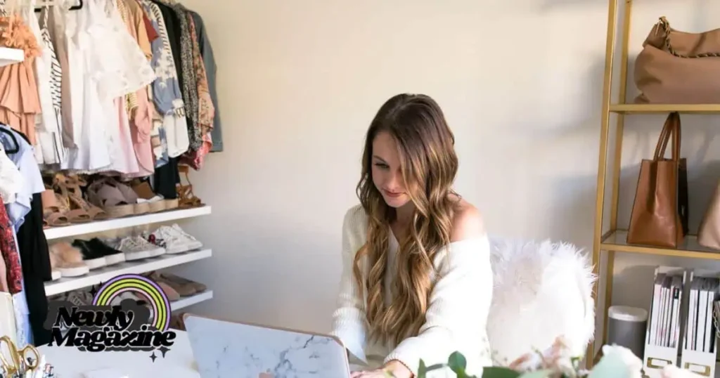 A woman sits at a desk, thoughtfully organizing her wardrobe, showcasing Daryl Ann Denner’s clothing brand.