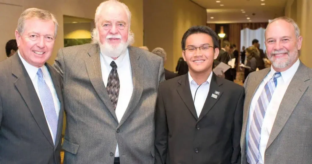 Three men in suits pose for a photo, highlighting Robert Plaster's notable contributions to the community.